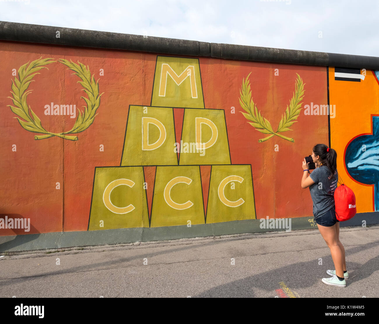 Tourist taking photograph of mural peint sur l'article original du mur de Berlin à l'East Side Gallery à Berlin, Allemagne Banque D'Images