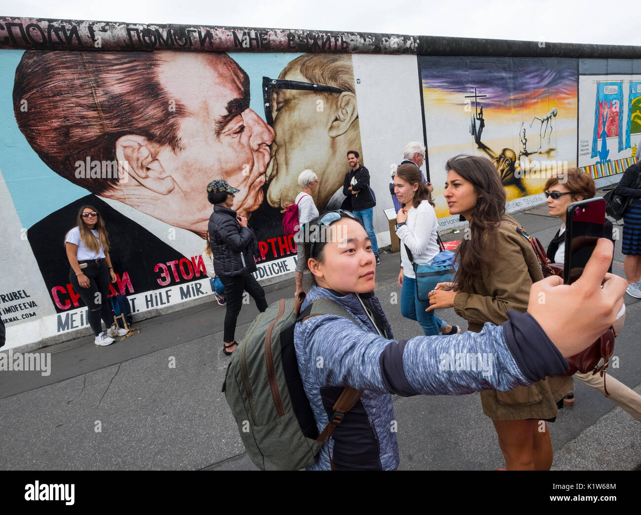 Tourist taking photograph of mural peint sur l'article original du mur de Berlin à l'East Side Gallery à Berlin, Allemagne Banque D'Images