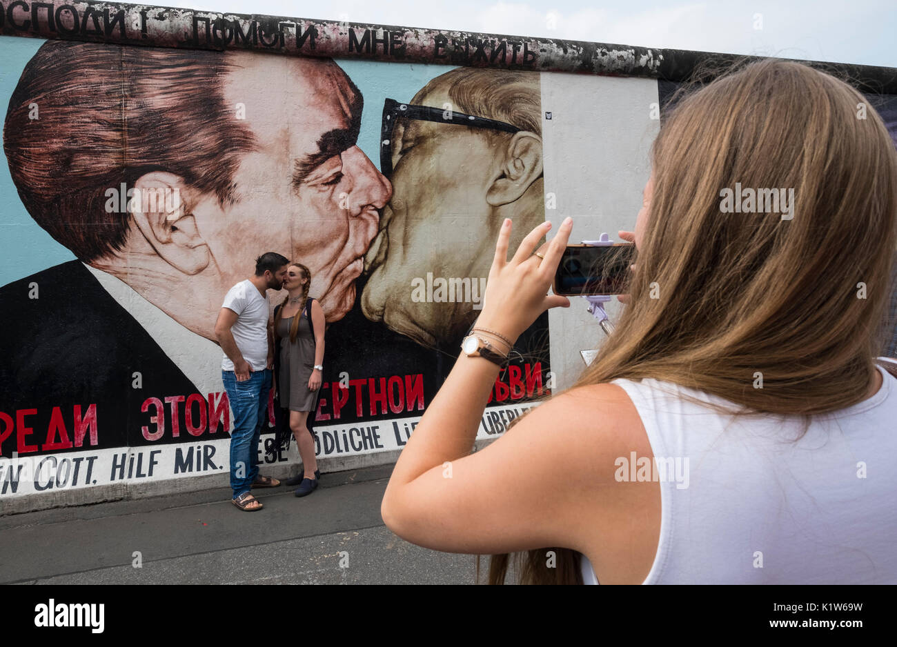 Tourist taking photograph of mural peint sur l'article original du mur de Berlin à l'East Side Gallery à Berlin, Allemagne Banque D'Images