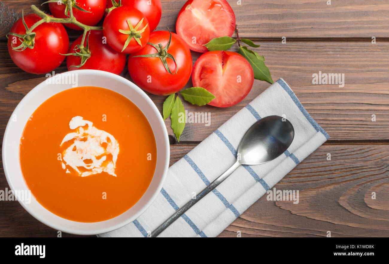 Soupe de tomate avec des tomates fraîches et crème servi sur une table en bois Banque D'Images