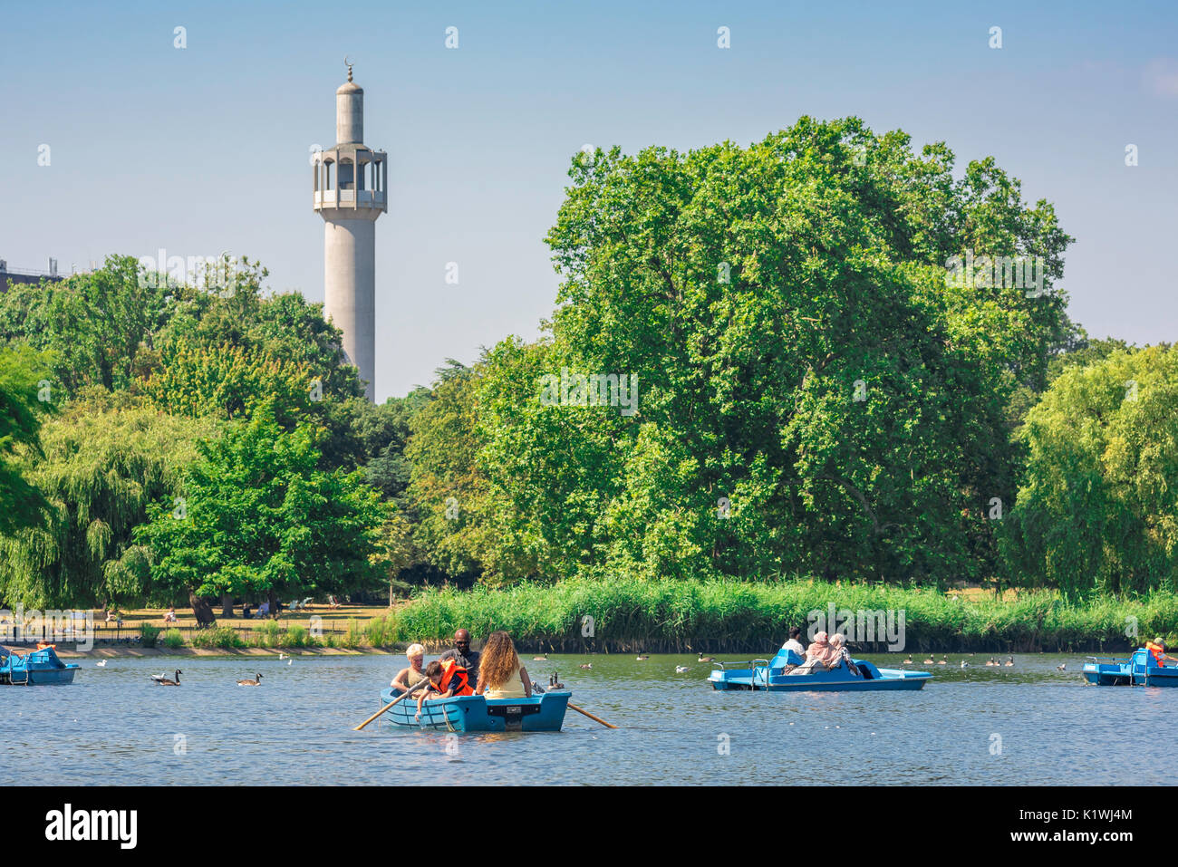 Regent's Park de Londres, la vue sur le lac de plaisance et les touristes appréciant un après-midi d'été avec le minaret de la mosquée centrale à l'arrière, au Royaume-Uni. Banque D'Images