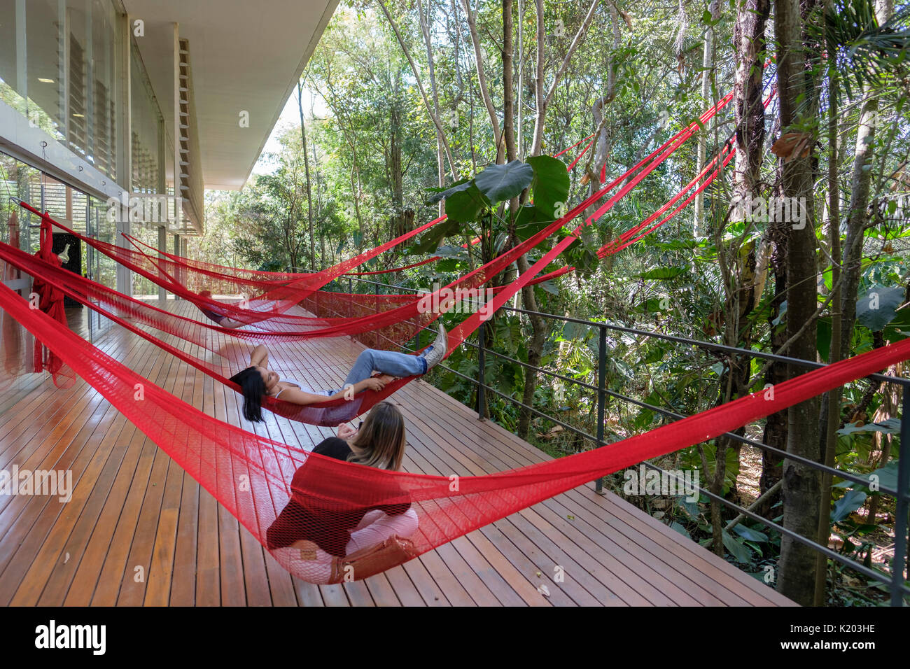 Les gens se reposant sur le rouge des hamacs suspendus à la galerie Tunga, Institut Culturel Inhotim, Brumadinho, Belo Horizonte, Minas Gerais, Brésil. Banque D'Images