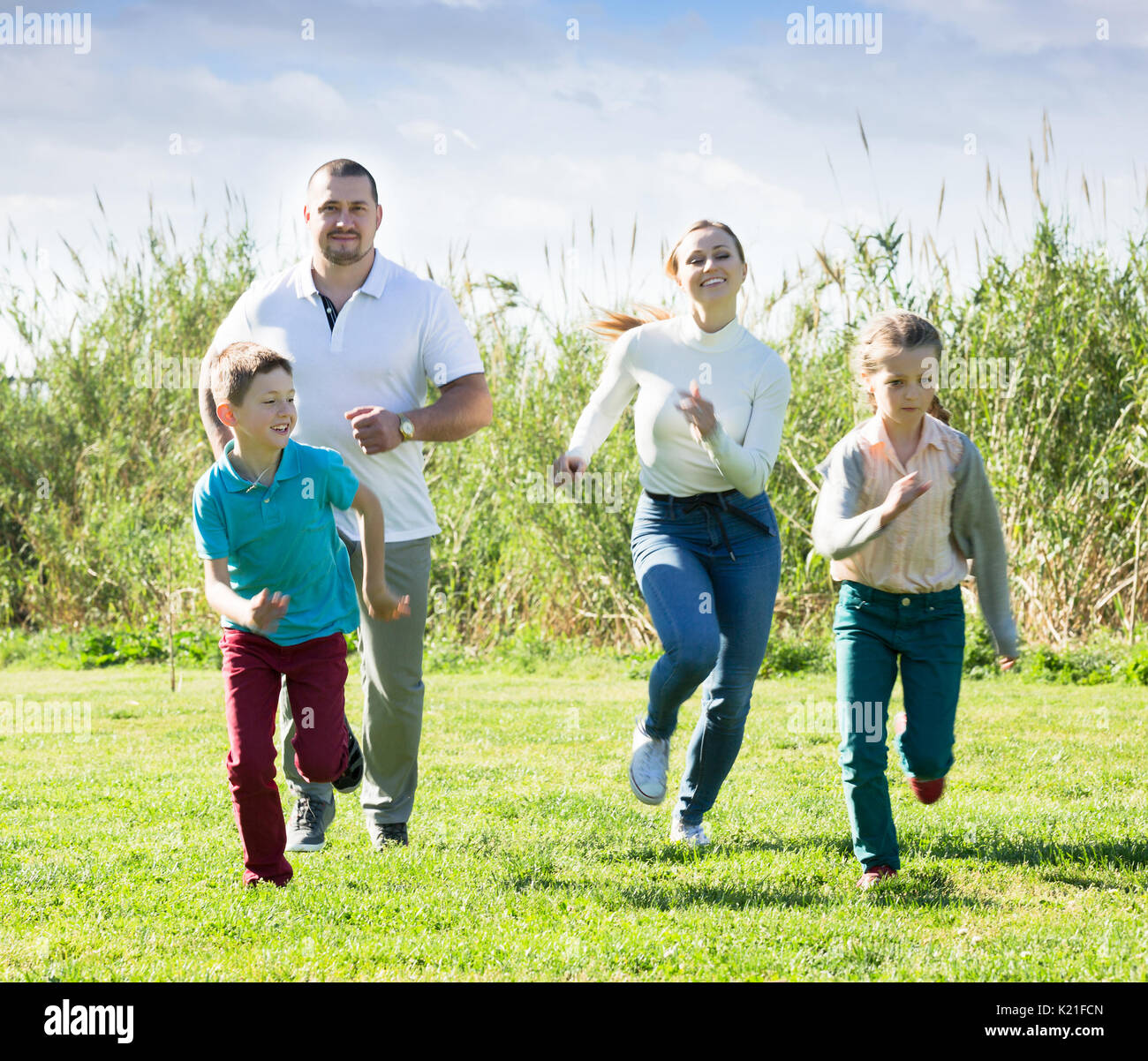 Famille de quatre personnes heureusement jouer et courir ensemble à l'extérieur. L'accent sur boy Banque D'Images