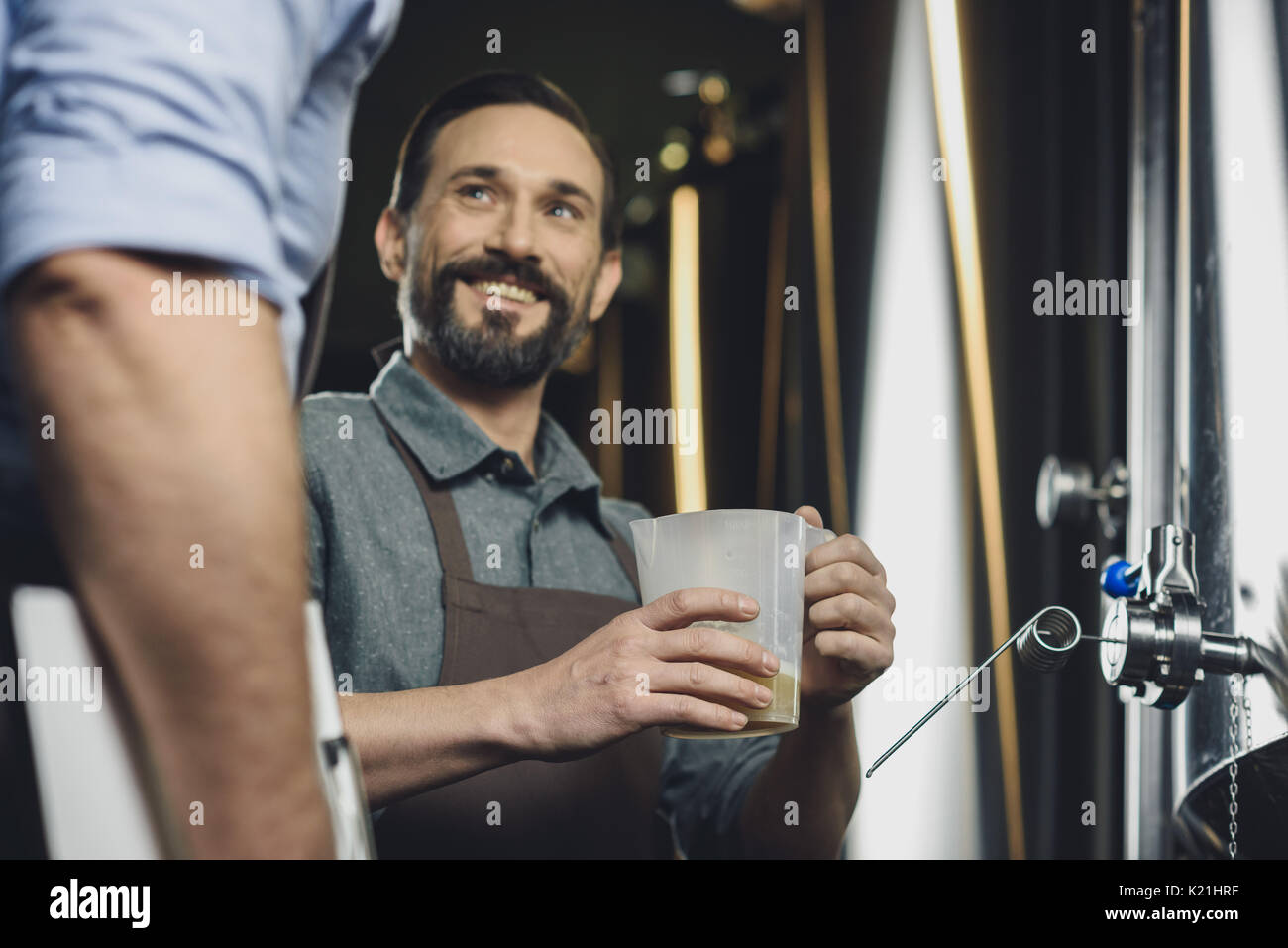 Brewer mâle en plastique avec cruche avec de la bière et en regardant son collègue Banque D'Images