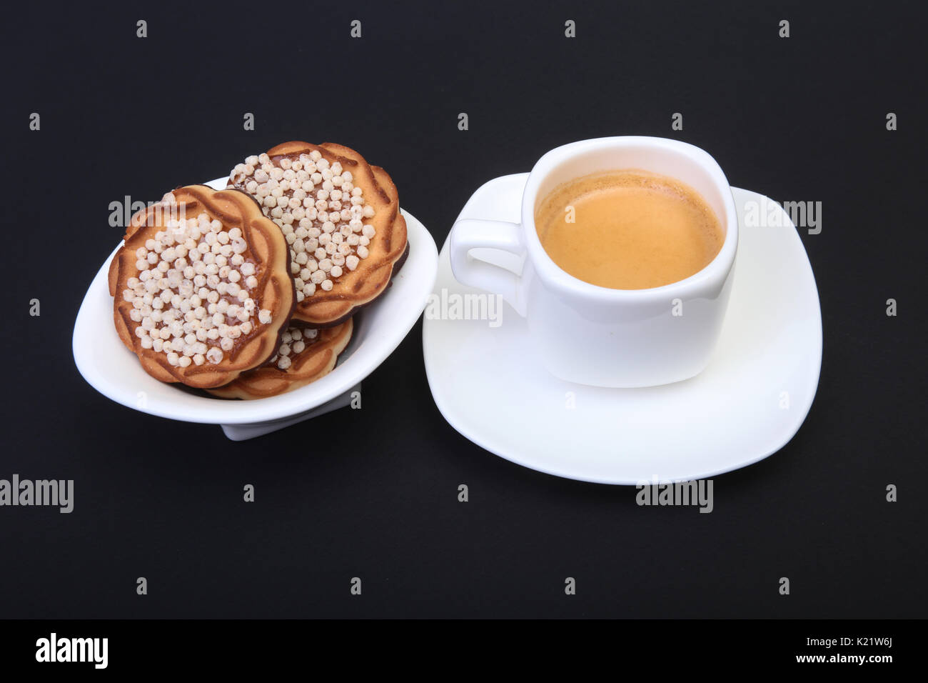 Dans l'espresso classique avec des gâteaux tasse blanche sur fond noir. Focus sélectif. Banque D'Images