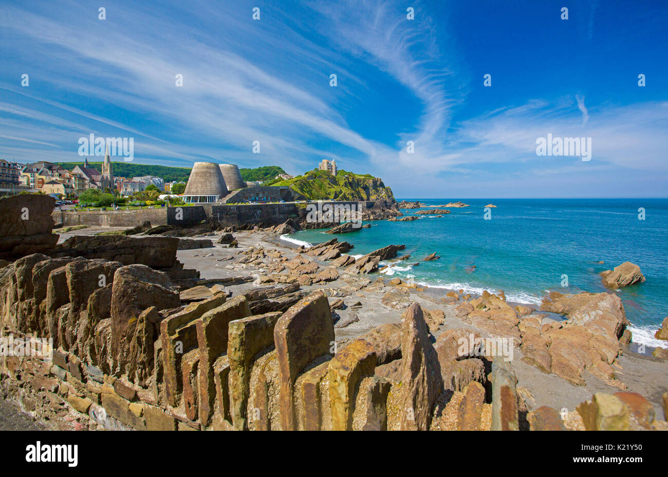 Ville tentaculaire ourlée par plage abritée, et des eaux bleues de l'océan léchant côte rocheuse sous ciel bleu à Ilfracombe, Devon, Angleterre Banque D'Images