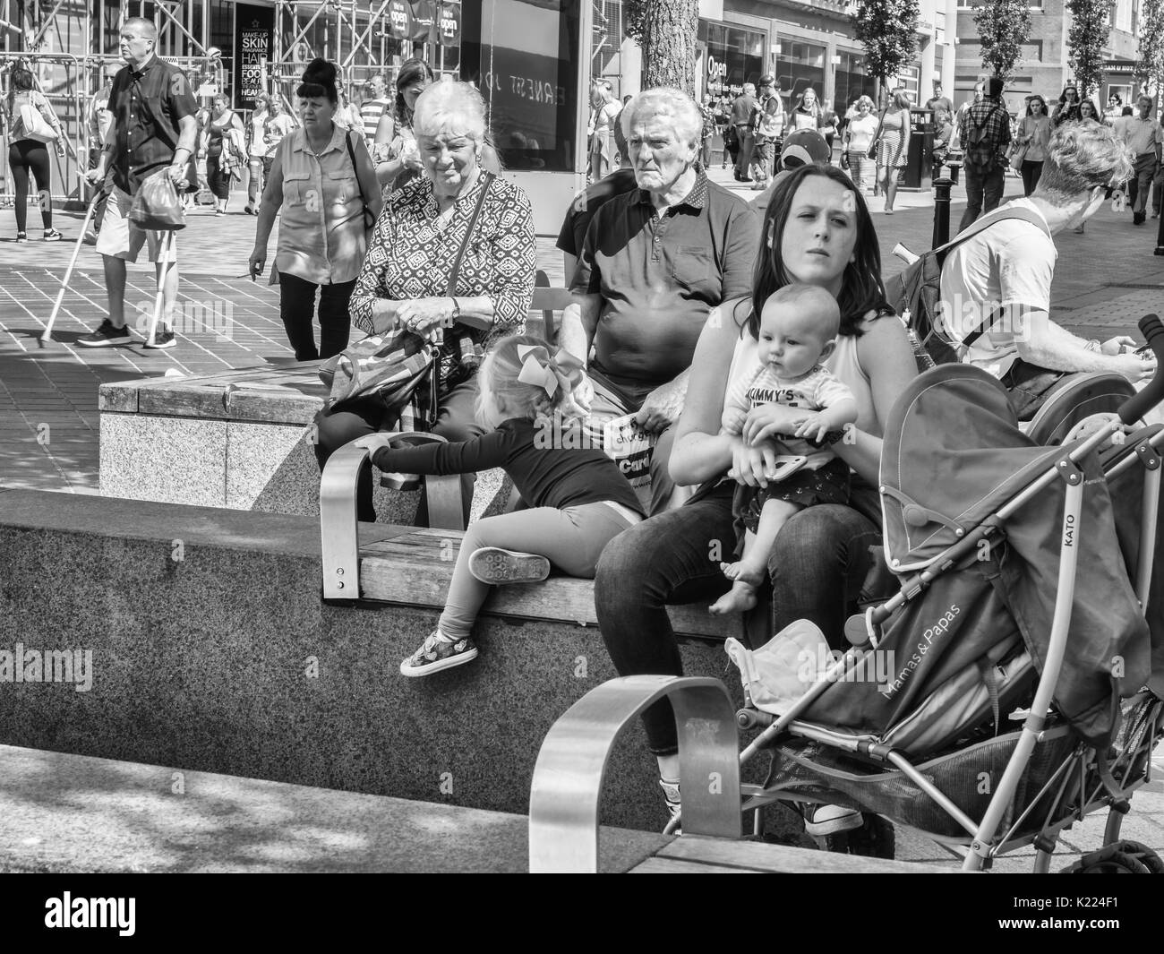 Mother sitting avec bébé & enfant vu par femme âgée. Liverpool, Angleterre, Royaume-Uni Banque D'Images