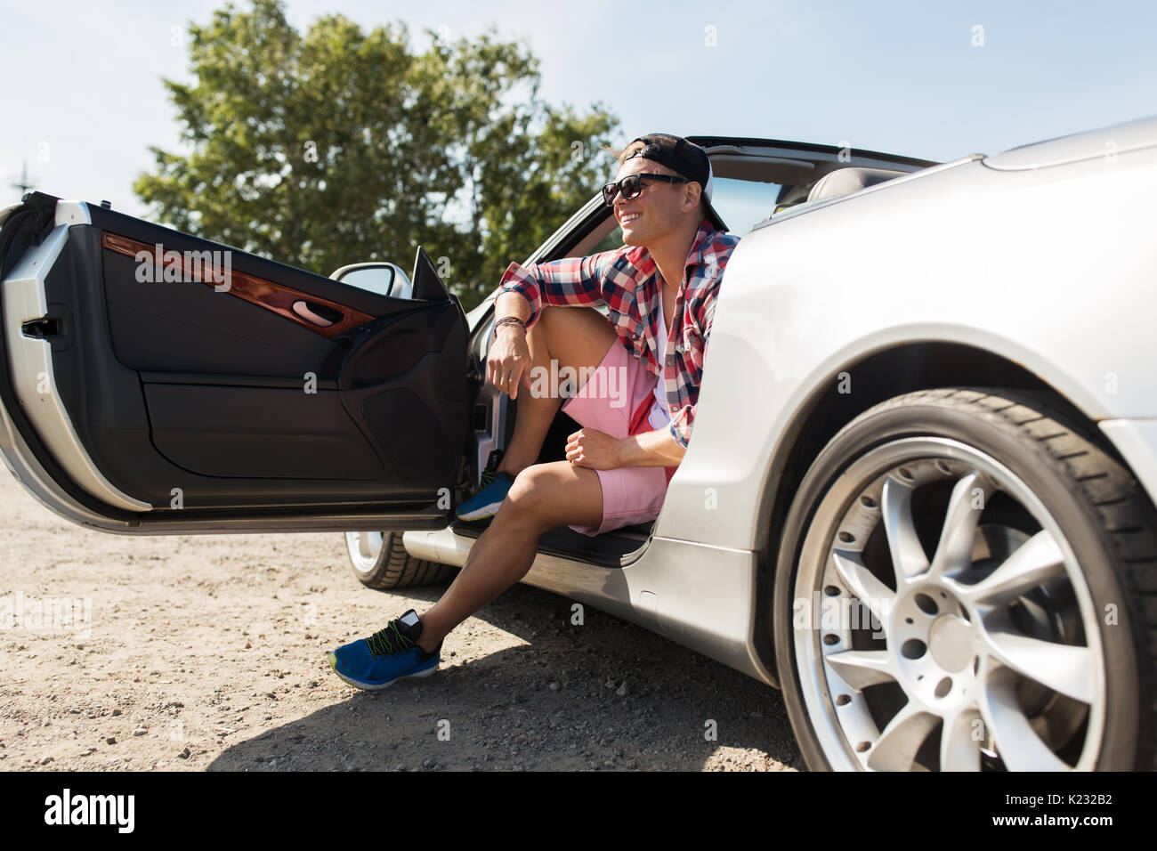 Happy young man sitting in convertible car Banque D'Images