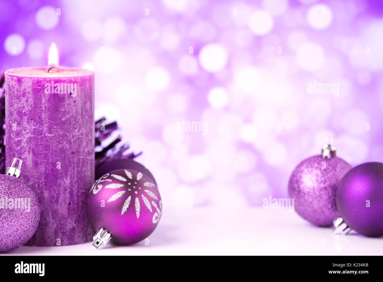 Boules de Noël pourpre et argent et une bougie devant defocused lights violet et blanc. Banque D'Images