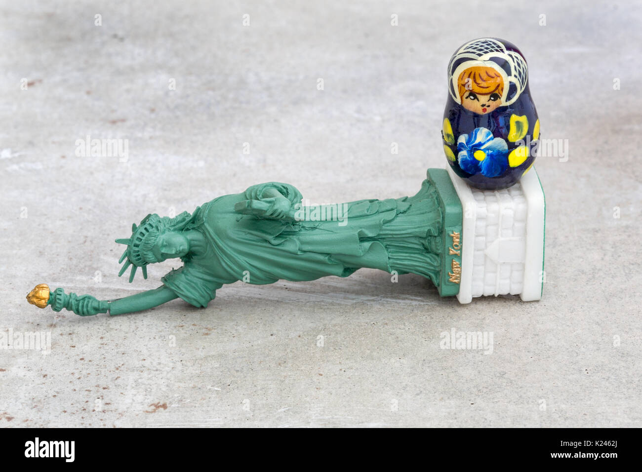 Un modèle d'une statue de la liberté tombés avec une petite poupée matriochka russe debout sur le dessus de celui-ci (concept) Banque D'Images