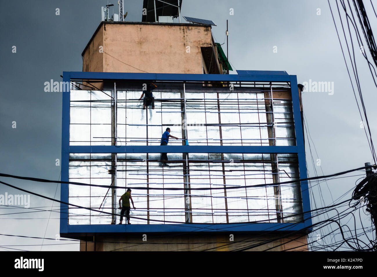 PATAN, NÉPAL - CIRCA Juillet 2017 : Hommes travaillant sur un panneau avec des nuages de mousson menaçante dans l'arrière-plan. Banque D'Images