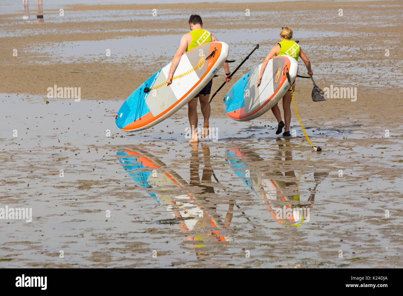 Bancs, Poole, Dorset, UK. Août 28, 2017. Météo France : belle chaude journée ensoleillée à bancs, comme les foules affluent à la station beach que les températures montent. En essayant de garder au frais dans la mer - paddleboarders marcher sur la mer avec des réflexions à marée basse dans le port de Poole. Credit : Carolyn Jenkins/Alamy Live News Banque D'Images