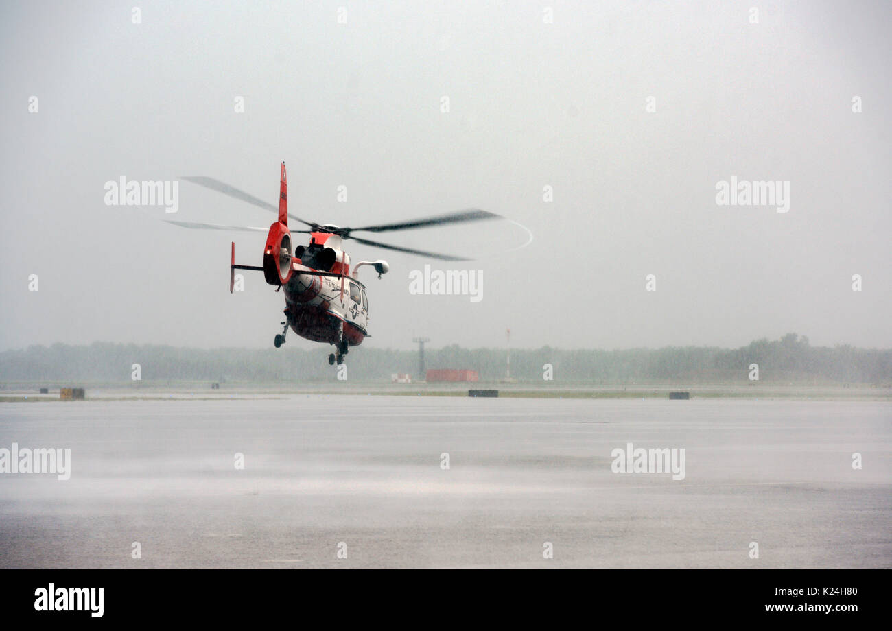 Une garde côtière des États-Unis MH-65 têtes hors de l'hélicoptère Dauphin en pluie sur une mission de sauvetage pour aider les résidents échoués après une inondation massive accablé de routes et de bâtiments dans toute la ville après le passage de l'ouragan Harvey le 27 août 2016 à Houston, Texas. Banque D'Images