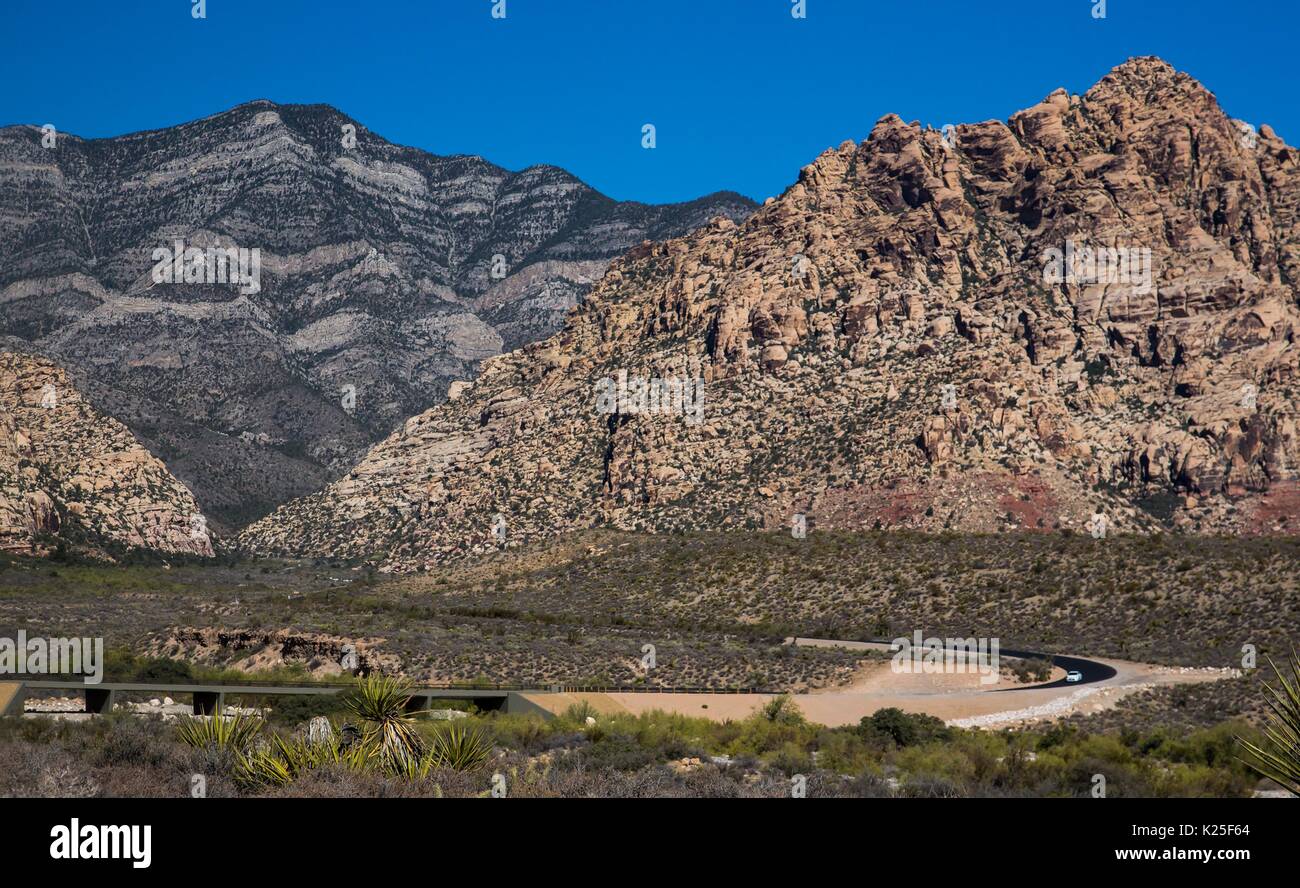 Une voiture de route est éclipsé par les formations de roche géant comme il se conduit par le Red Rock Canyon National Conservation Area, 27 septembre 2016 près de Las Vegas, Nevada. Banque D'Images
