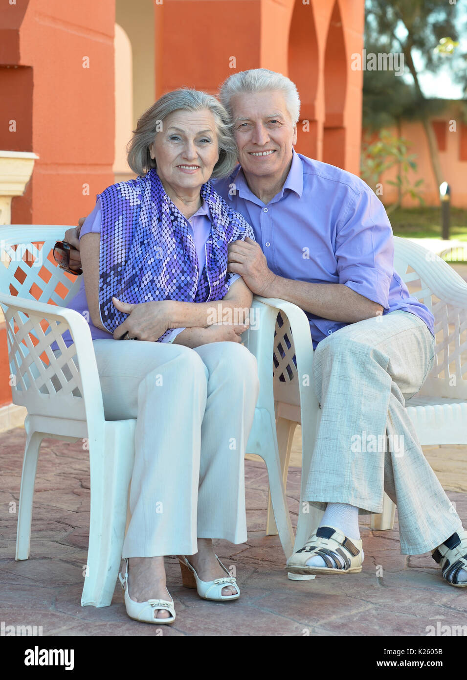 Happy senior couple assis sur des chaises en plastique à l'extérieur Banque D'Images