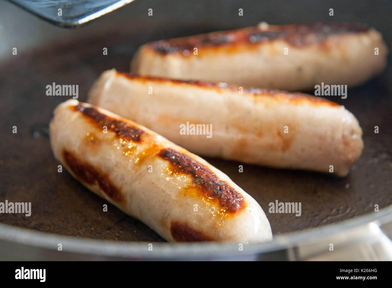 Trois saucisses dans une poêle de cuisson Banque D'Images