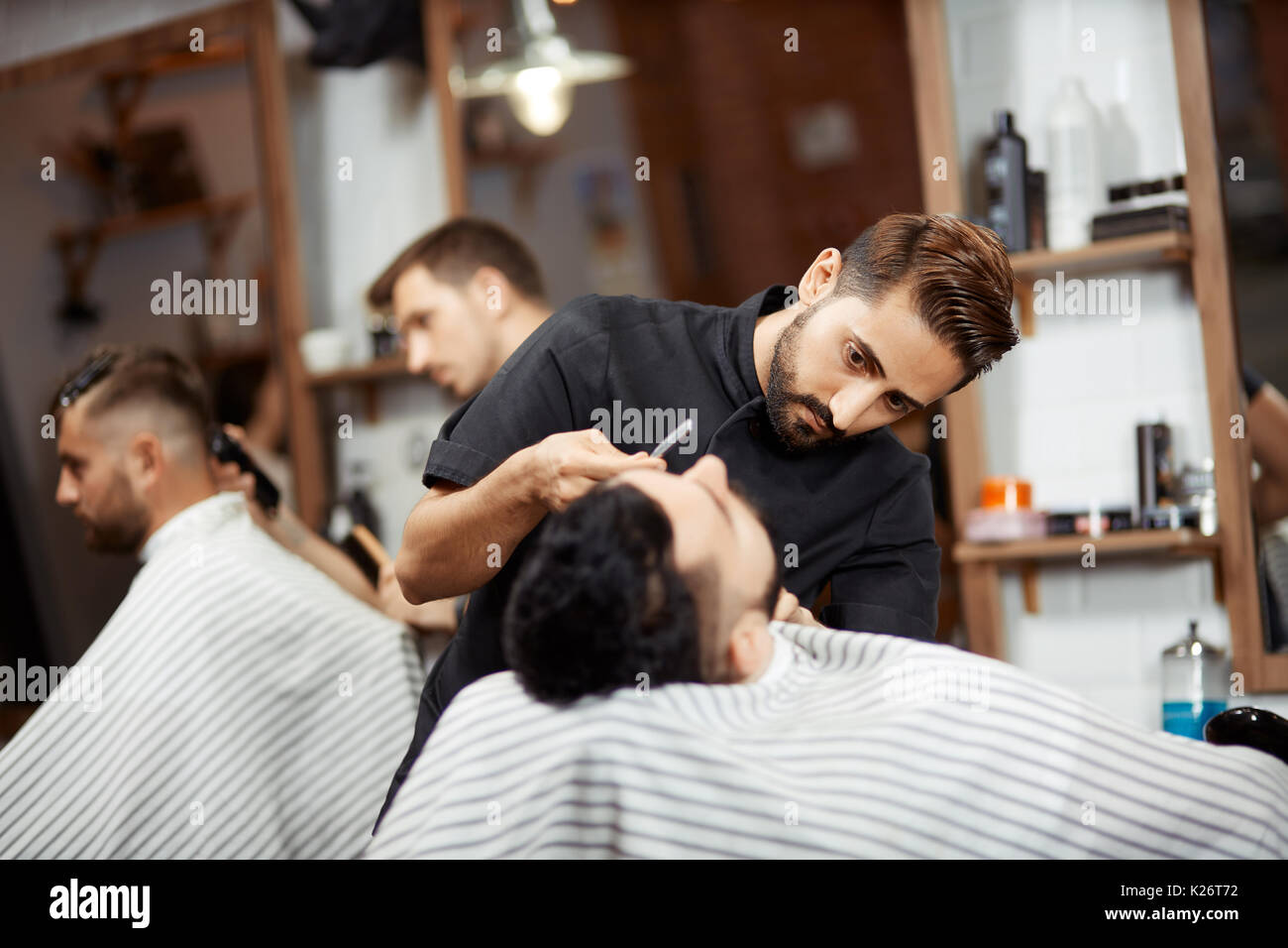 Deux stylistes, ce pain coupe coupe pour les clients dans un salon de coiffure. Banque D'Images