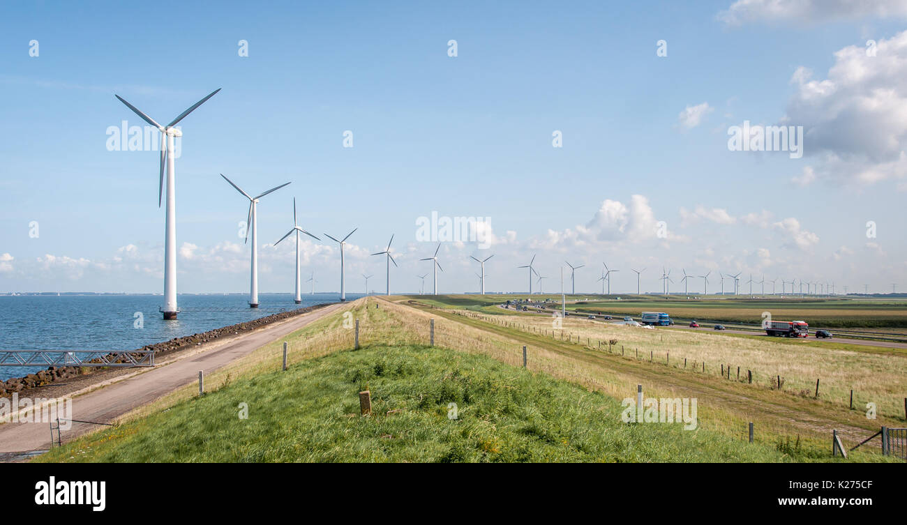 Longue rangée de moulins à vent à côté de la route, avec beaucoup de trafic Banque D'Images