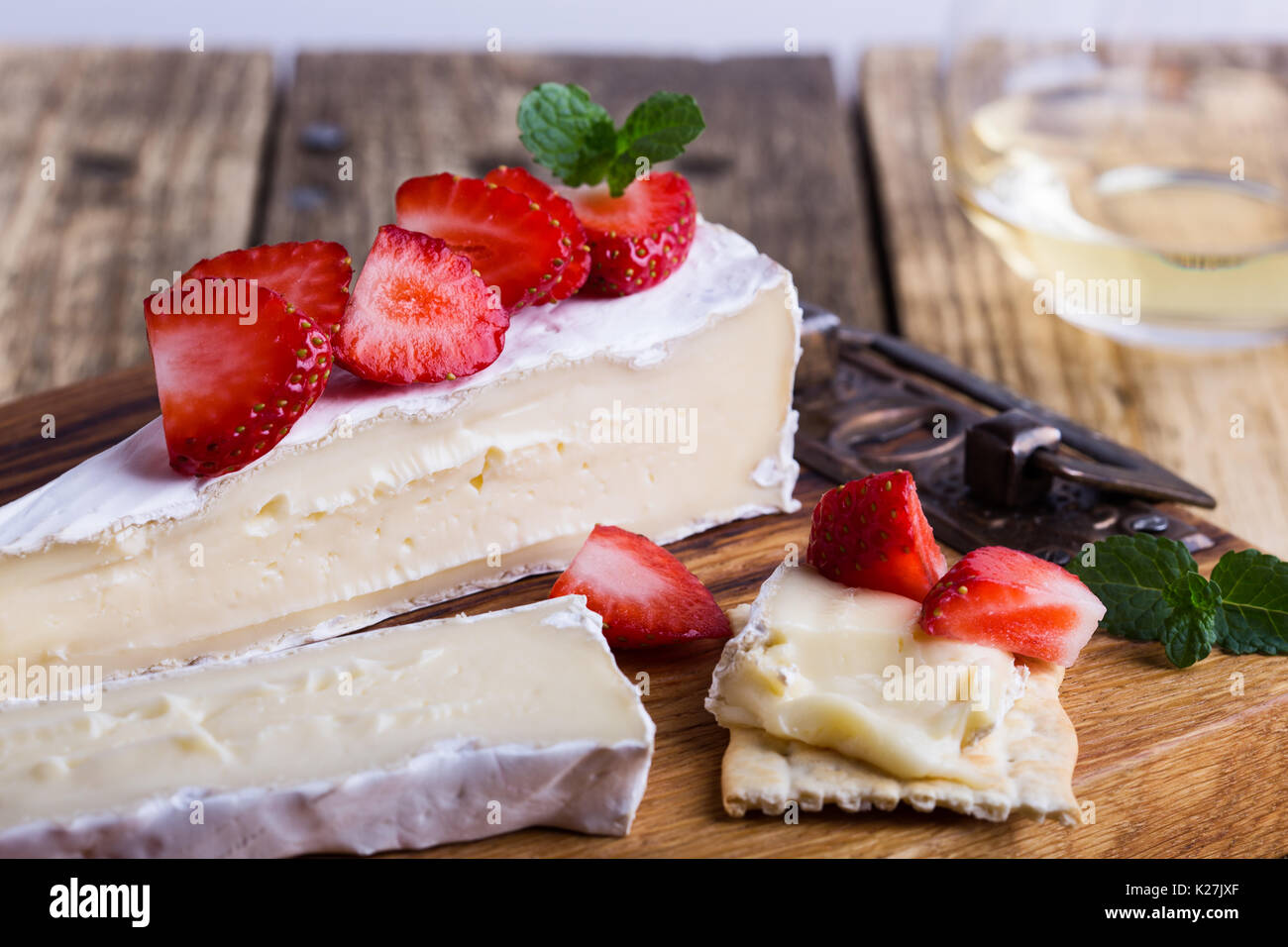 Plateau de fromages. Brie avec fraises et menthe sur planche de bois rustique Banque D'Images