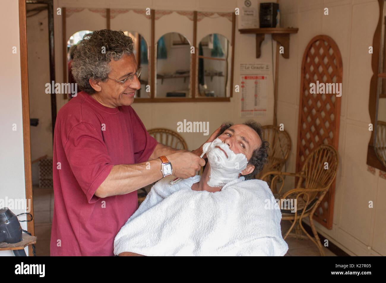 En man blir rakad hos barberaren, Toscana, Italie. Banque D'Images