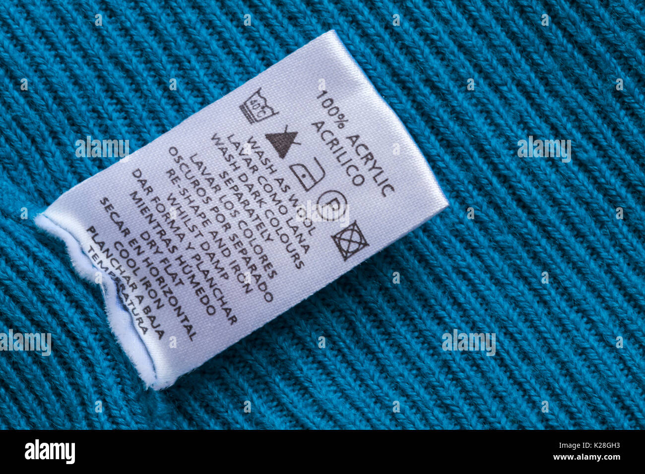 Symboles de lavage soins et des instructions sur l'étiquette dans le  Cavalier bleu 100 % acrylique laine lavage comme se laver les couleurs  foncées séparément en français et en espagnol Photo Stock -