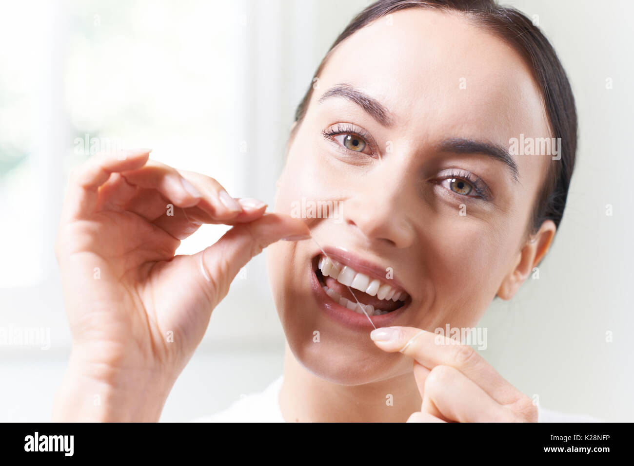 Femme dans la salle de bains la soie dentaire dents blanches Banque D'Images