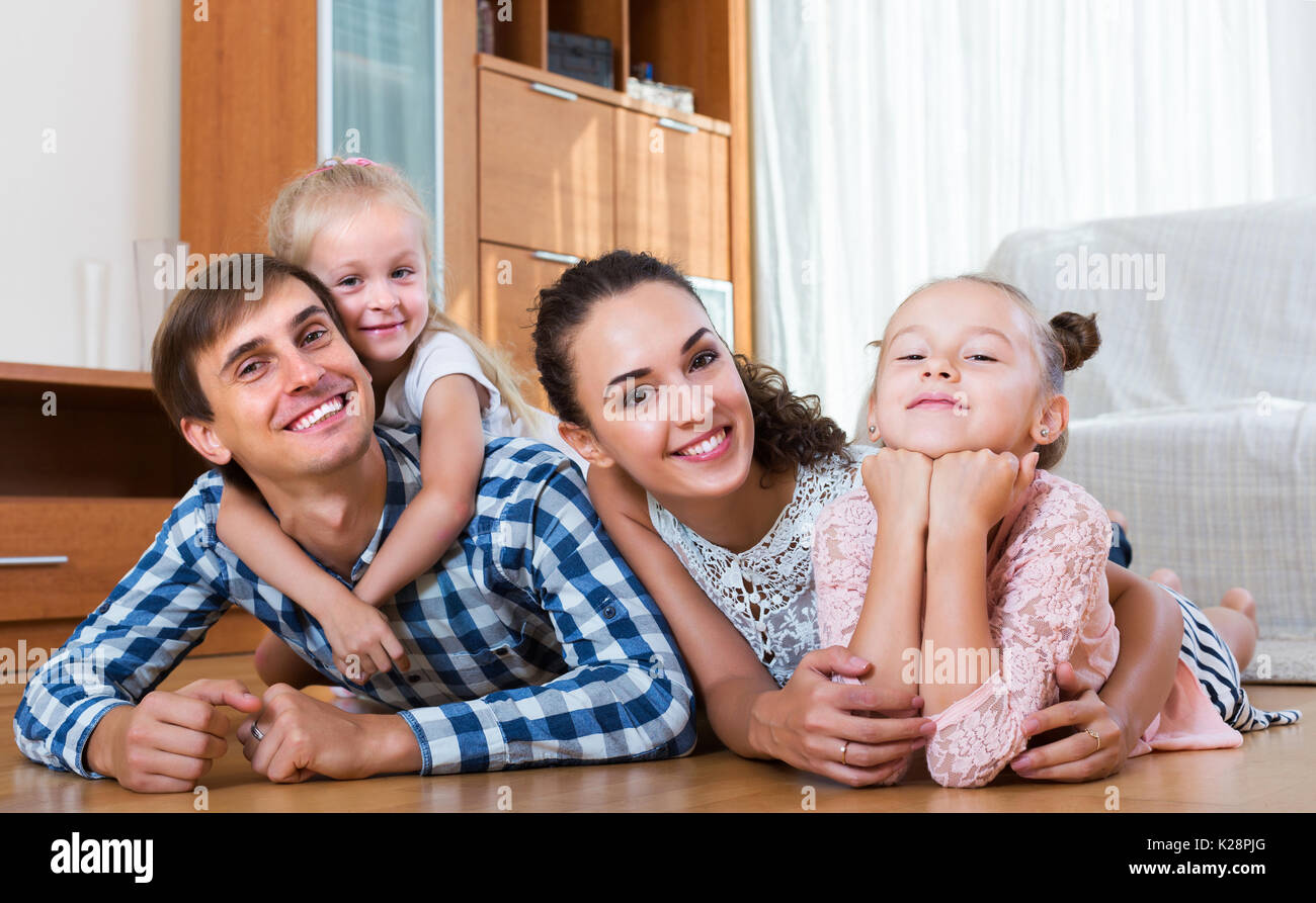 Famille heureuse détendue de quatre posant dans l'intérieur domestique Banque D'Images