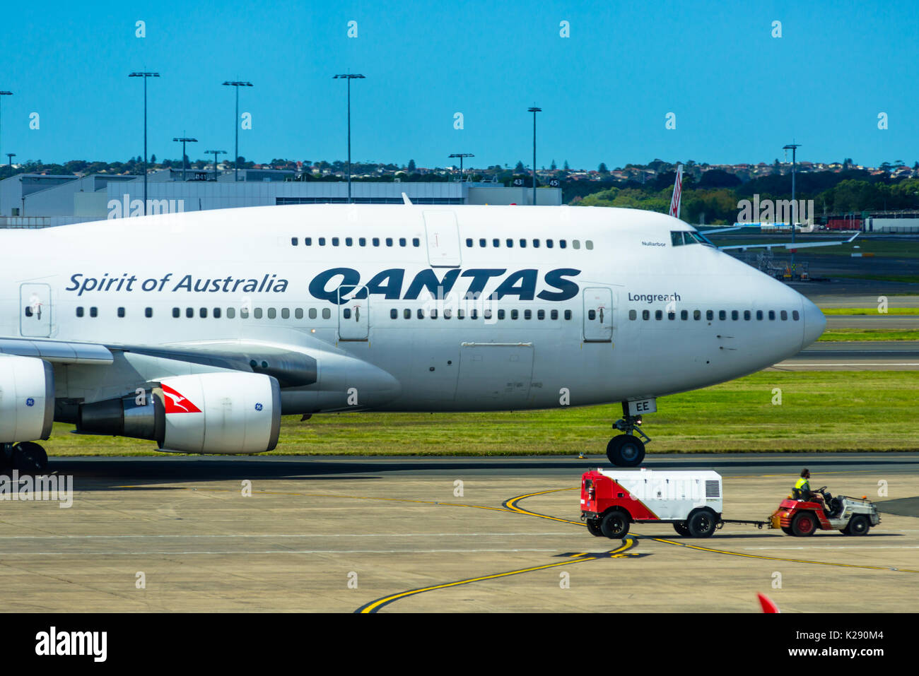 Un jumbo jet 747 Qantas à côté d'un véhicule des bagages à l'aéroport international de Sydney, Nouvelle-Galles du Sud, Australie. Banque D'Images