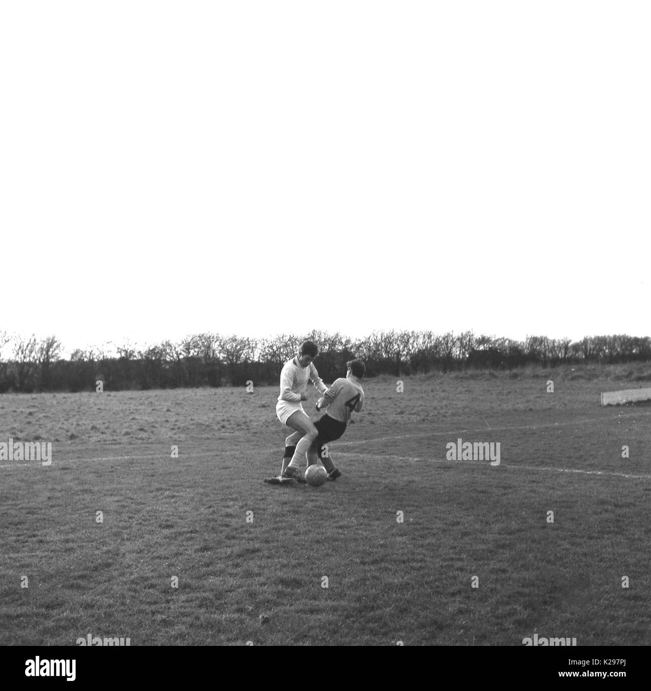 1964, historique, Angleterre, Royaume-Uni, deux homme sundaly les joueurs de football ligue amateur exigeant ou s'attaquer les uns les autres pour la balle. Banque D'Images