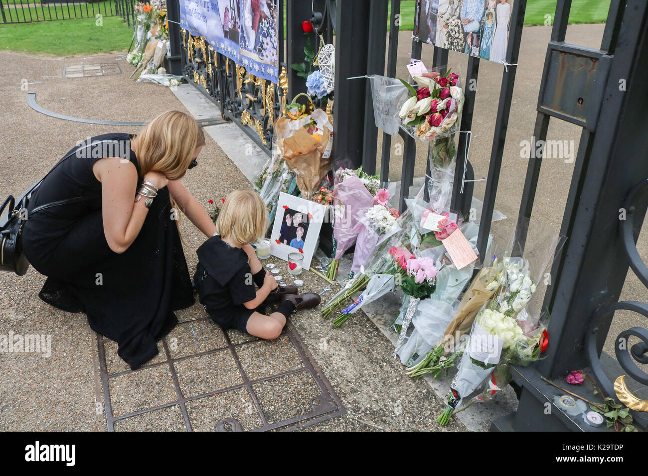 Londres, Royaume-Uni. Août 29, 2017. Une mère et d'enfant en ce qui concerne leur rémunération avec tributs floraux en dehors de Kensington Palace avec deux jours avant le 20e anniversaire de la mort de Diana Princesse de Galles qui devint connu comme la princesse du peuple a été tragiquement tué dans un accident de voiture mortel à Paris le 31 août 1997. Credit : amer ghazzal/Alamy Live News Banque D'Images