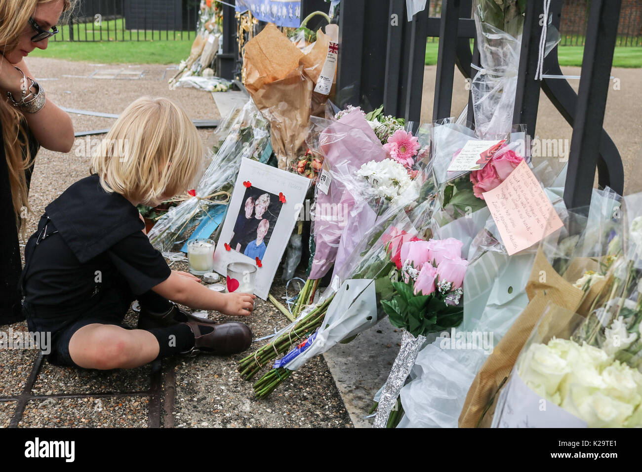 Londres, Royaume-Uni. Août 29, 2017. Une mère et d'enfant en ce qui concerne leur rémunération avec tributs floraux en dehors de Kensington Palace avec deux jours avant le 20e anniversaire de la mort de Diana Princesse de Galles qui devint connu comme la princesse du peuple a été tragiquement tué dans un accident de voiture mortel à Paris le 31 août 1997. Credit : amer ghazzal/Alamy Live News Banque D'Images