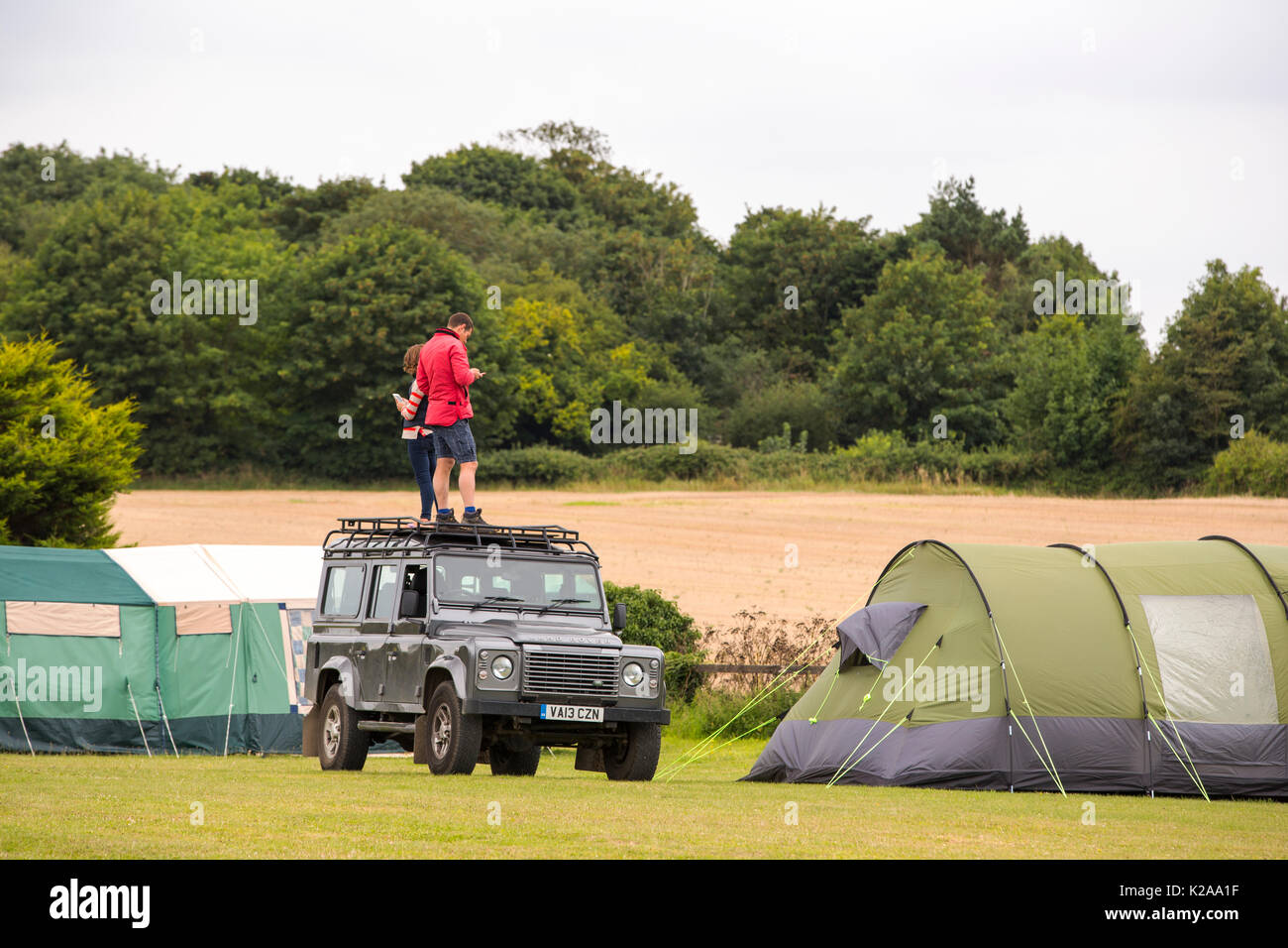 Un couple d'essayer d'obtenir un signal de téléphone sur le toit de leur Landrover sur un camping dans le CLAJ sur la côte nord du comté de Norfolk, au Royaume-Uni. Banque D'Images