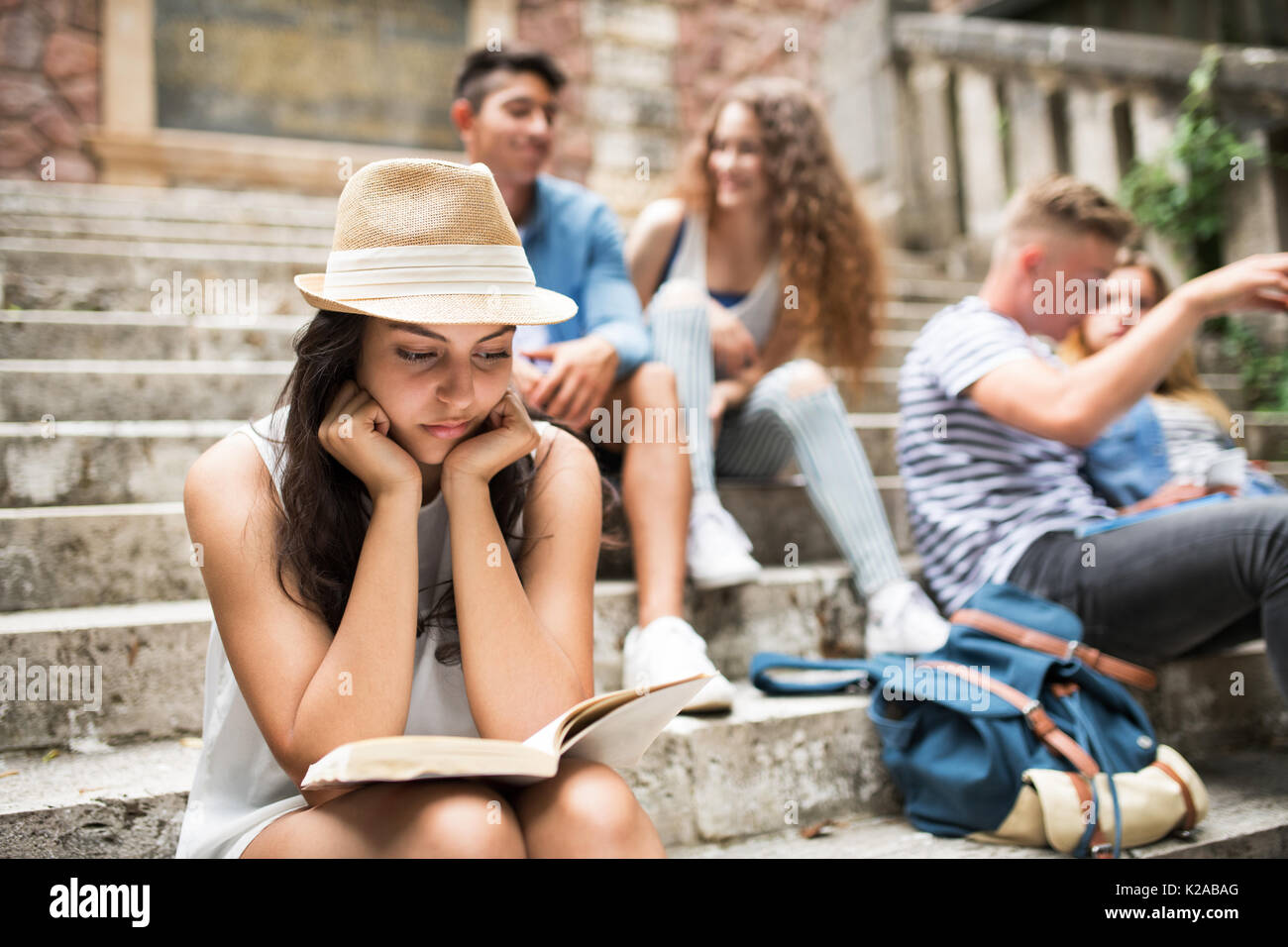 Teenage student girl sitting on marches de pierre de la lecture d'un livre. Banque D'Images