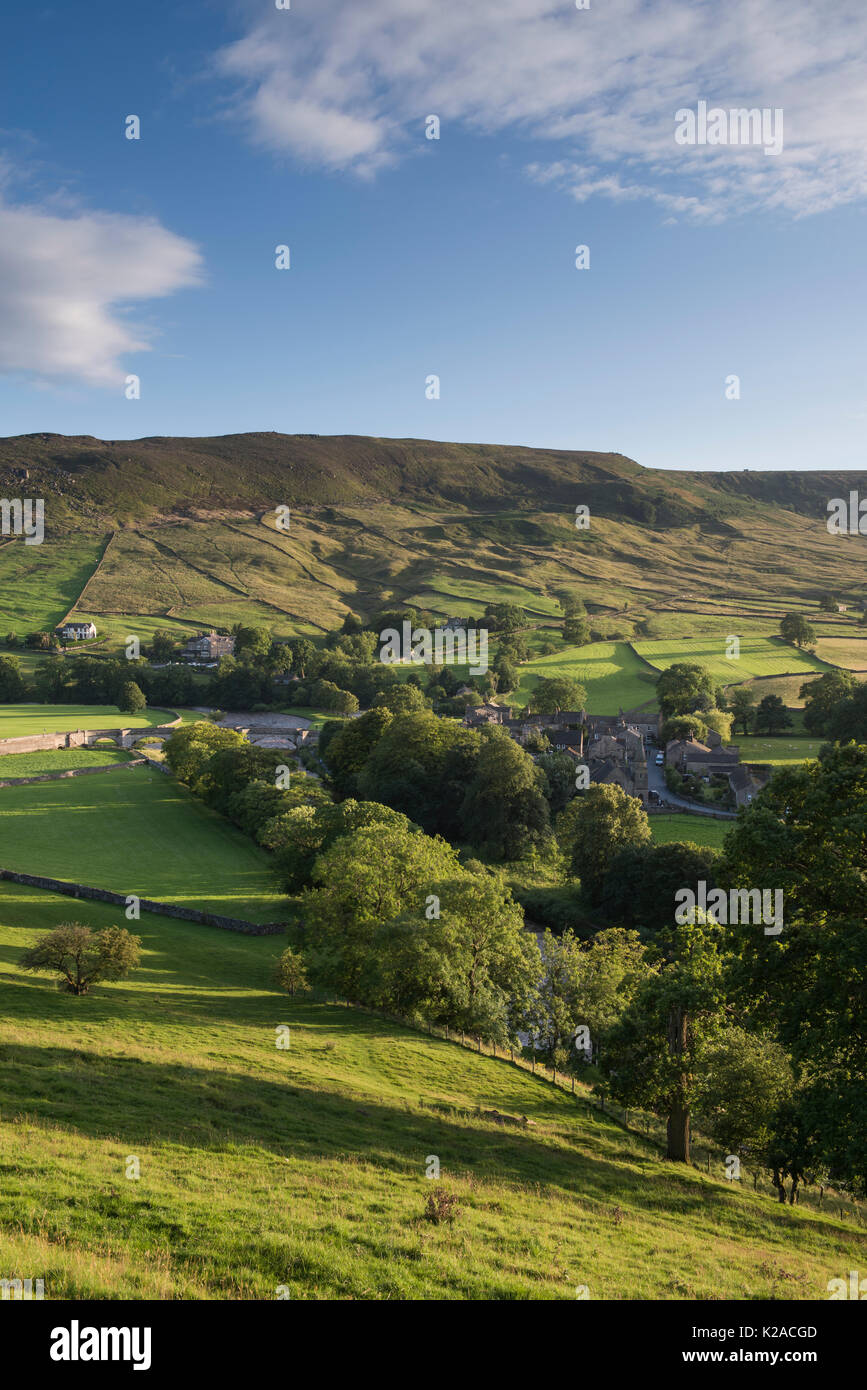 Voir plus haut belle, ensoleillée du Yorkshire village de Tonbridge dans la vallée par la rivière Wharfe et en pente abrupte, vert, colline au-delà - France, FR, UK. Banque D'Images
