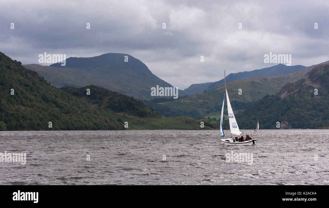 De collines et sous ciel gris, les gens sont dans de petits bateaux à voile sur Ullswater - voir à Glenridding et Penrith, Lake District, England, UK. Banque D'Images