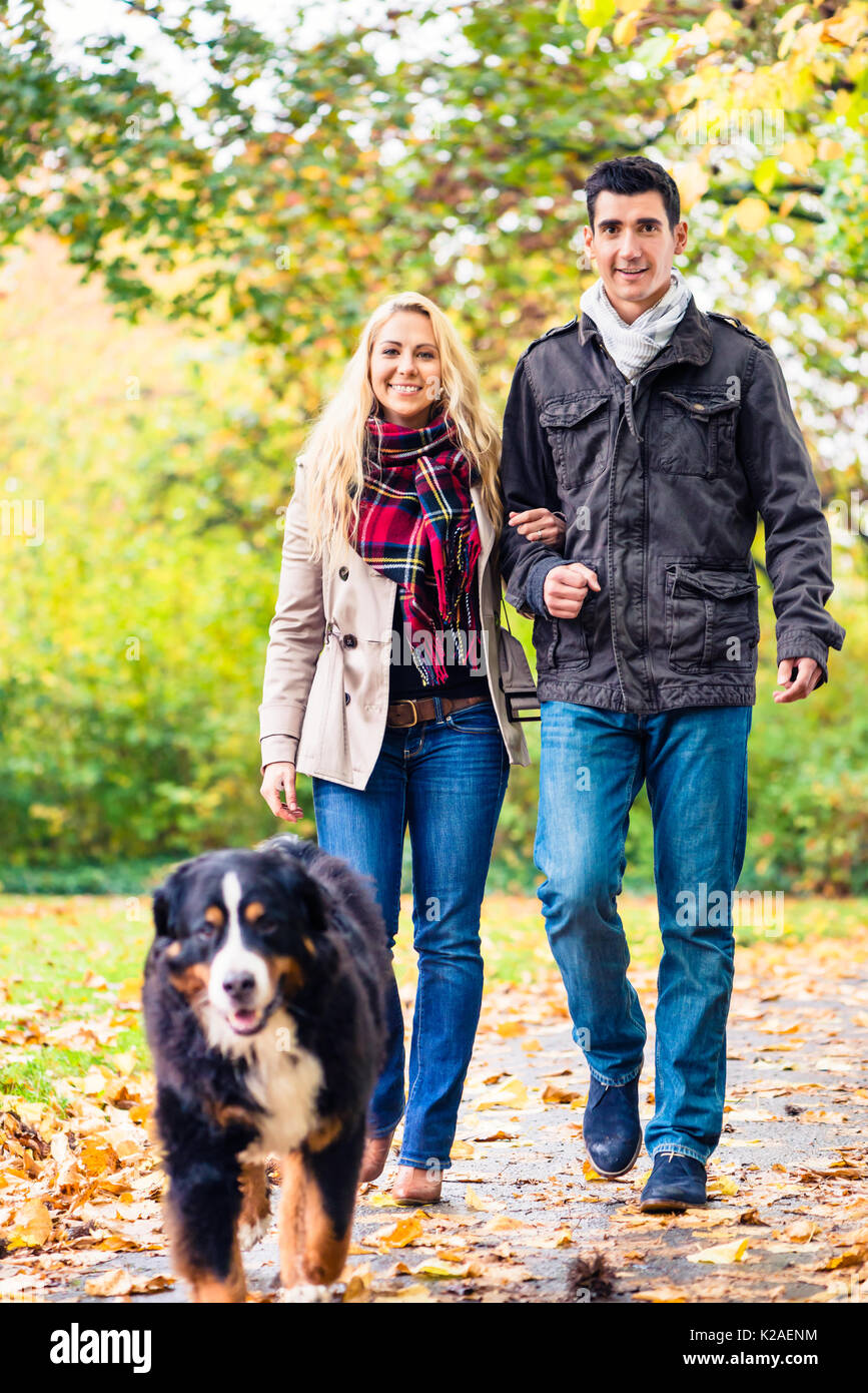 La femme et l'homme au chien ayant l'automne à pied Banque D'Images