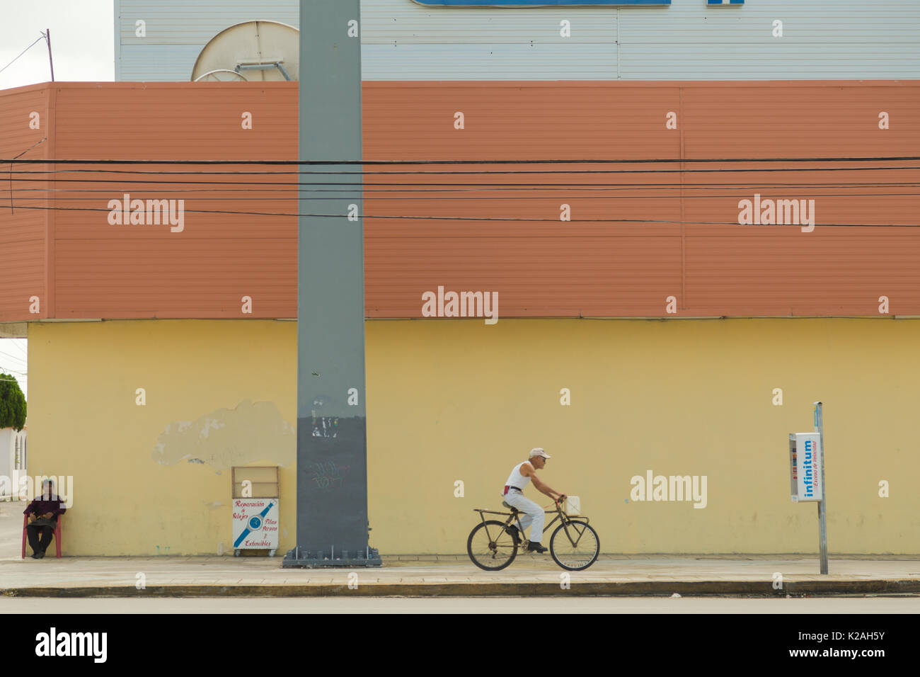 Une rue d'un vélo homme et un autre homme assis dans le coin de rue à Cancun, au Mexique. Banque D'Images
