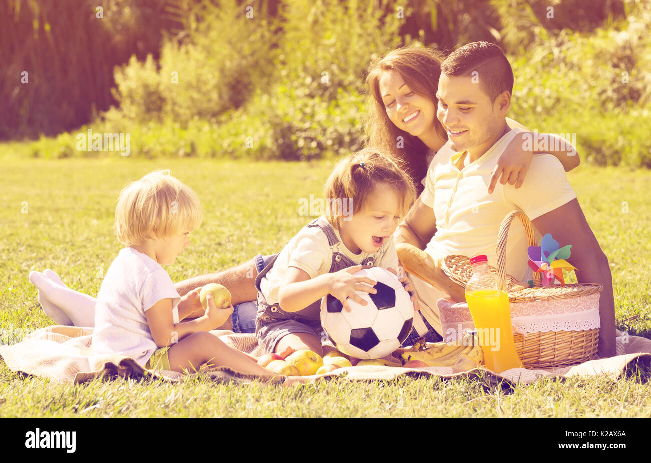 Heureux jeune famille de quatre having picnic à Meadow. L'accent sur l'homme Banque D'Images