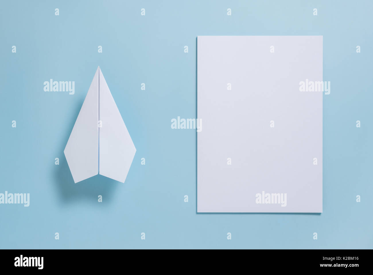 Mise à plat de l'avion en papier blanc et le papier blanc sur fond de couleur bleu pastel Banque D'Images