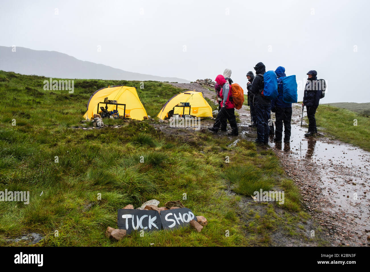 Randonnée Les randonneurs par Tuck Shop tentes sur West Highland Way chemin sentier point le plus élevé en haut de l'Escalier Diables dans la pluie. Glen Coe, Highland, Scotland, UK Banque D'Images