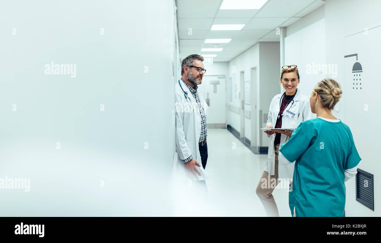 L'équipe médicale de discuter dans le couloir à l'hôpital. Discuter avec des collègues médecin mature tout en se tenant dans le couloir de l'hôpital. Banque D'Images