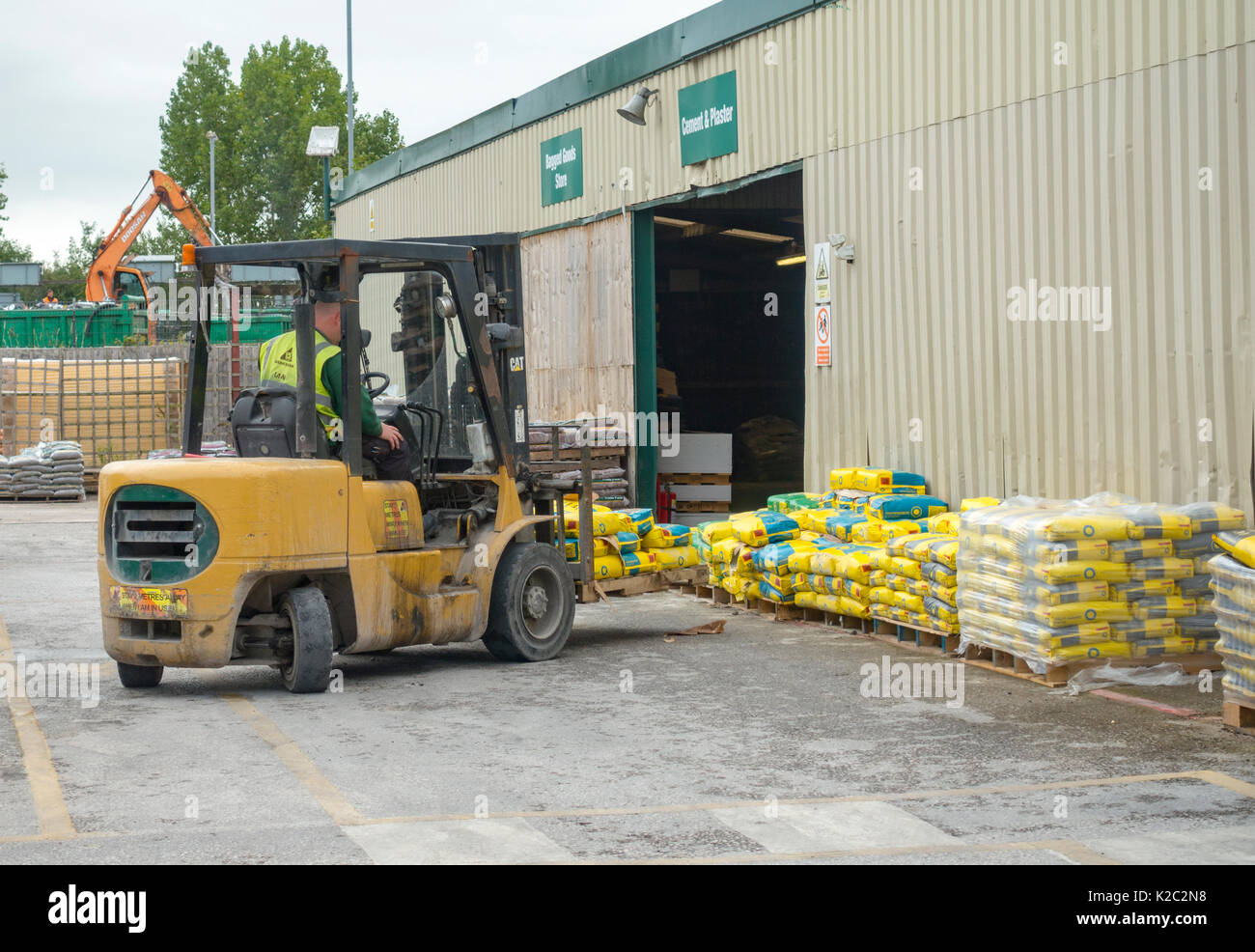 Travis Perkins agrafeuse chauffeur de camion déménagement sacs de ciment à l'extérieur dans la cour des constructeurs à Winsford, Cheshire Banque D'Images