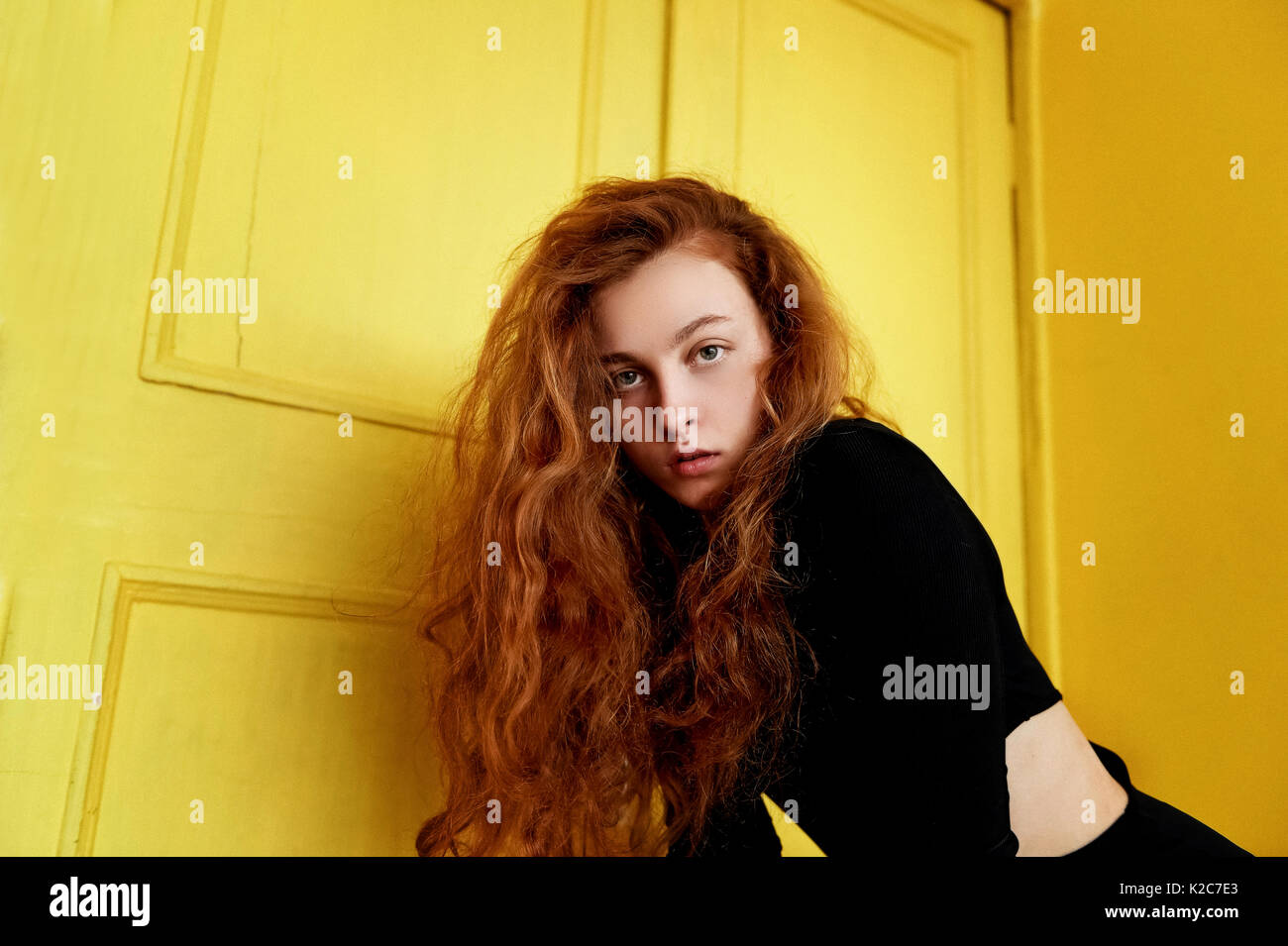 Les tests du modèle. Belle jeune fille rousse avec des cheveux bouclés. couleur naturelle. Grand contraste avec portes en bois jaune Photo Stock -  Alamy