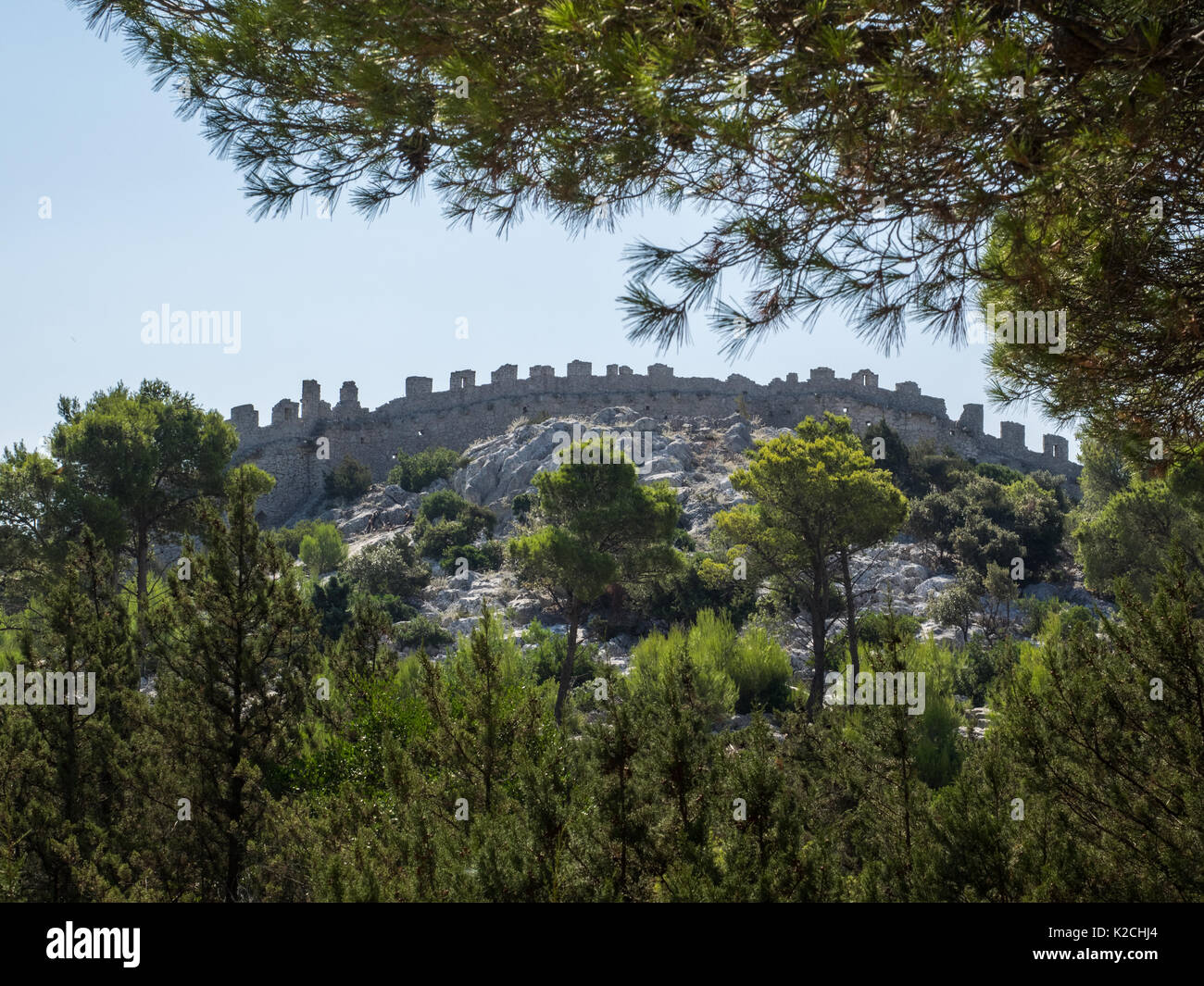 Vue d'un ancien mur de pierre ruines à mâchicoulis et remparts entouré de bois d'arbres forestiers côte Croate ciel bleu clair Banque D'Images