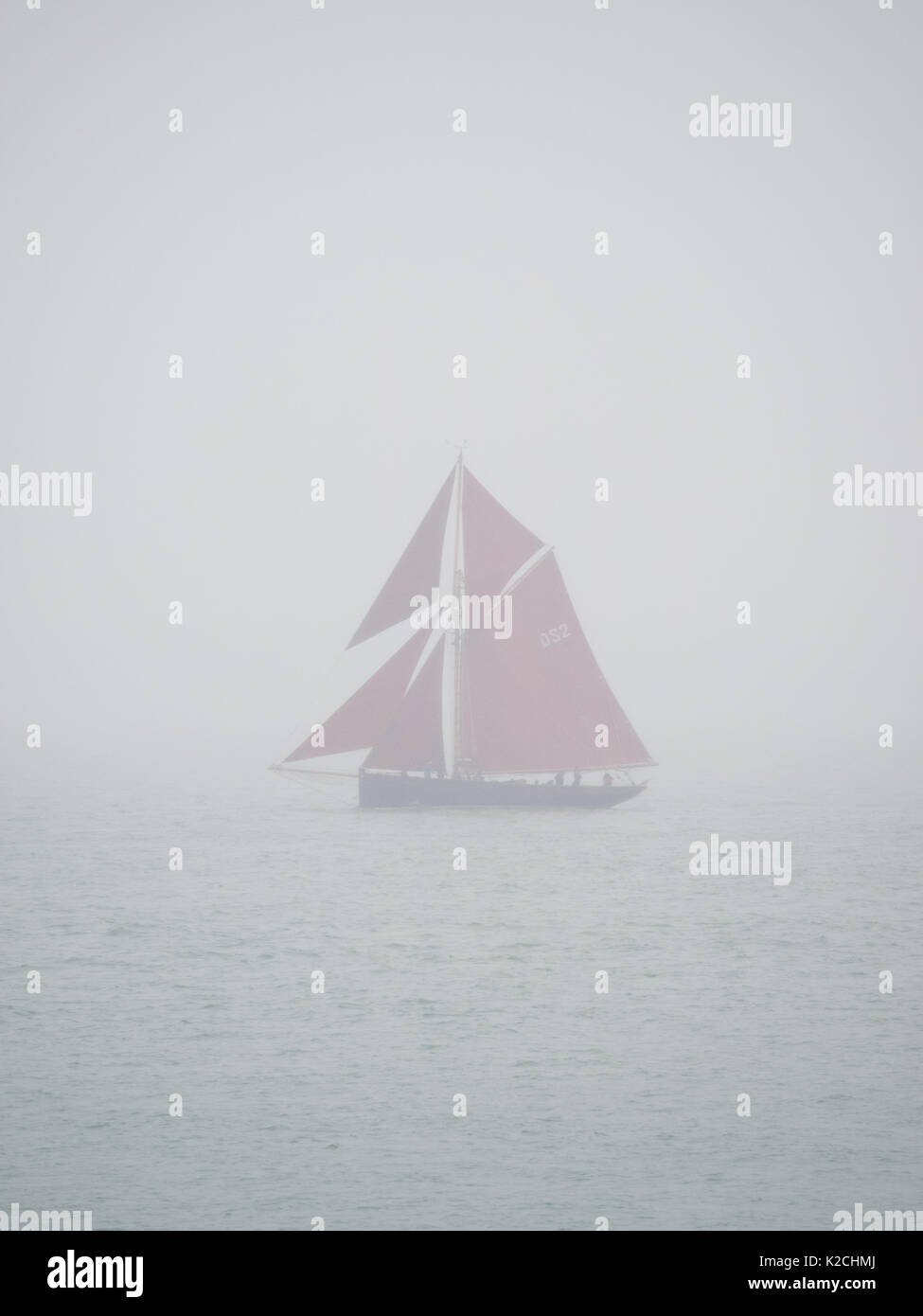 Un seul pilote en bois cutter classic yacht à voile voiles rouge sur l'eau calme dans le brouillard brouillard brouillard misty gris gris le ciel Une mauvaise visibilité le mauvais temps Banque D'Images