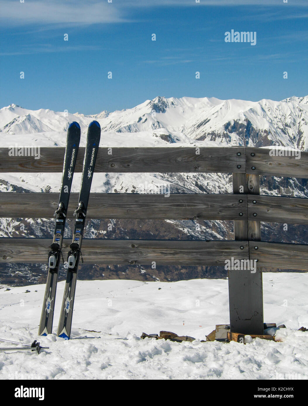 Une paire de skis deux repos gauche appuyé debout sur une clôture de la poste et des chemins de montagne sous ciel bleu clair et les montagnes background Banque D'Images
