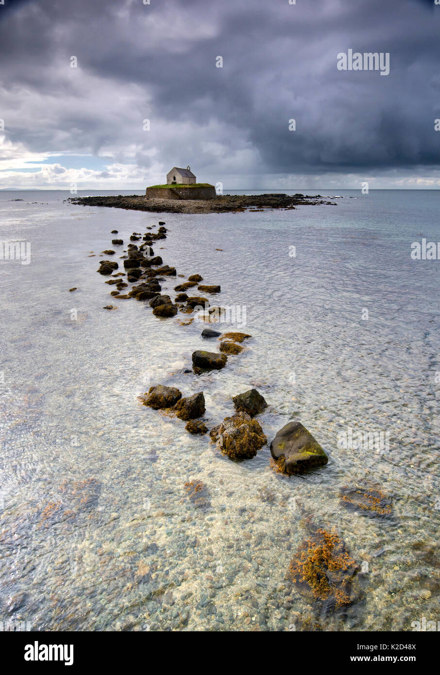 Sombres nuages sur l'église St Cwyfan, sur une île minuscule dans Cwyfan Porth, près de l'Aberffraw, Ile d'Anglesey, au Pays de Galles, avril 2014. Banque D'Images