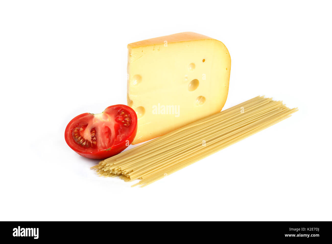 Gros morceau de fromage près de spaghetti et de tomate sur fond blanc Banque D'Images