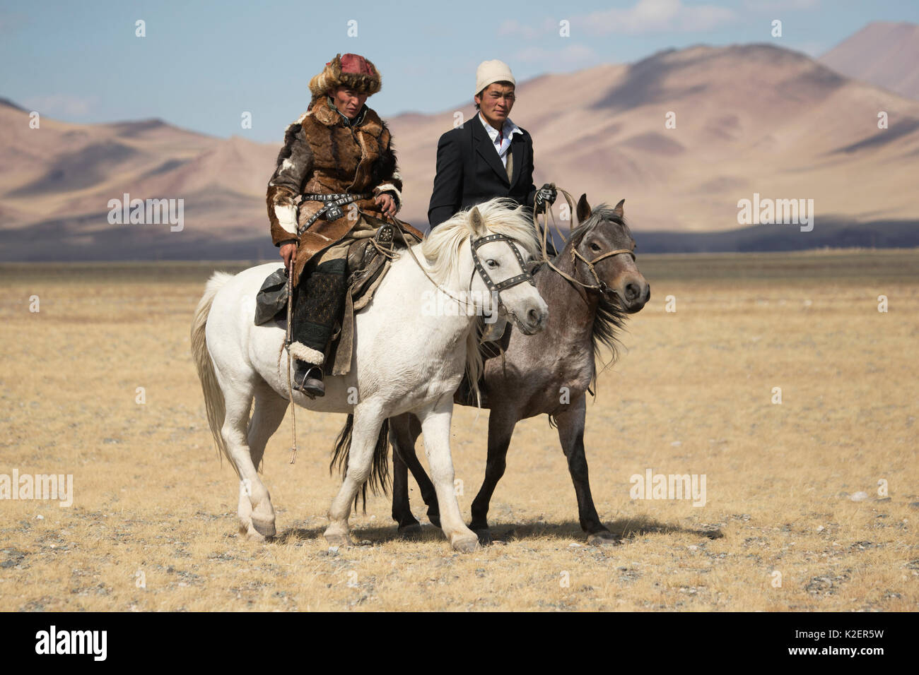 Eagle Hunter (à gauche) et musulmans rider à pied montés sur leurs chevaux de Mongolie, à l'Aigle, près de Sagsai Festival Chasseurs, Bayan-Ulgii Aymag, la Mongolie. Septembre 2014.. Banque D'Images