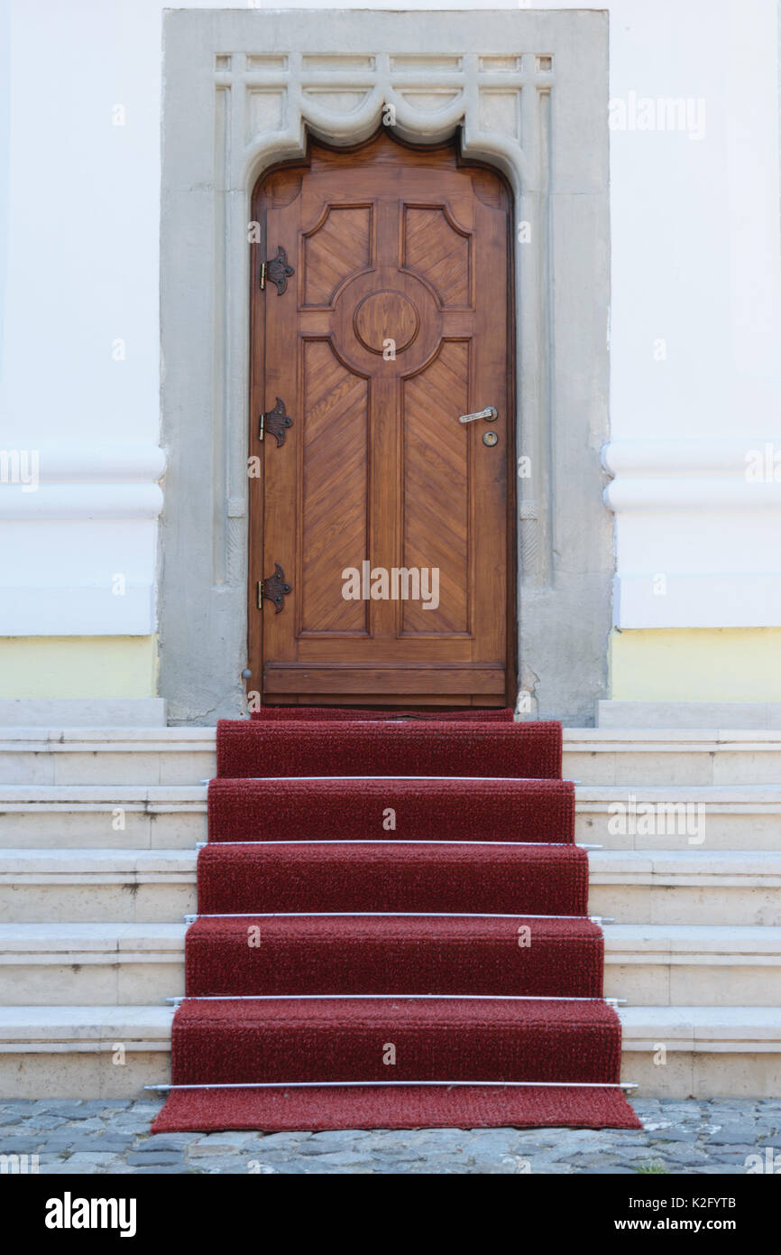 Porte en bois massif, les murs de béton artistique et tapis rouge sur l'entrée Escalier Banque D'Images